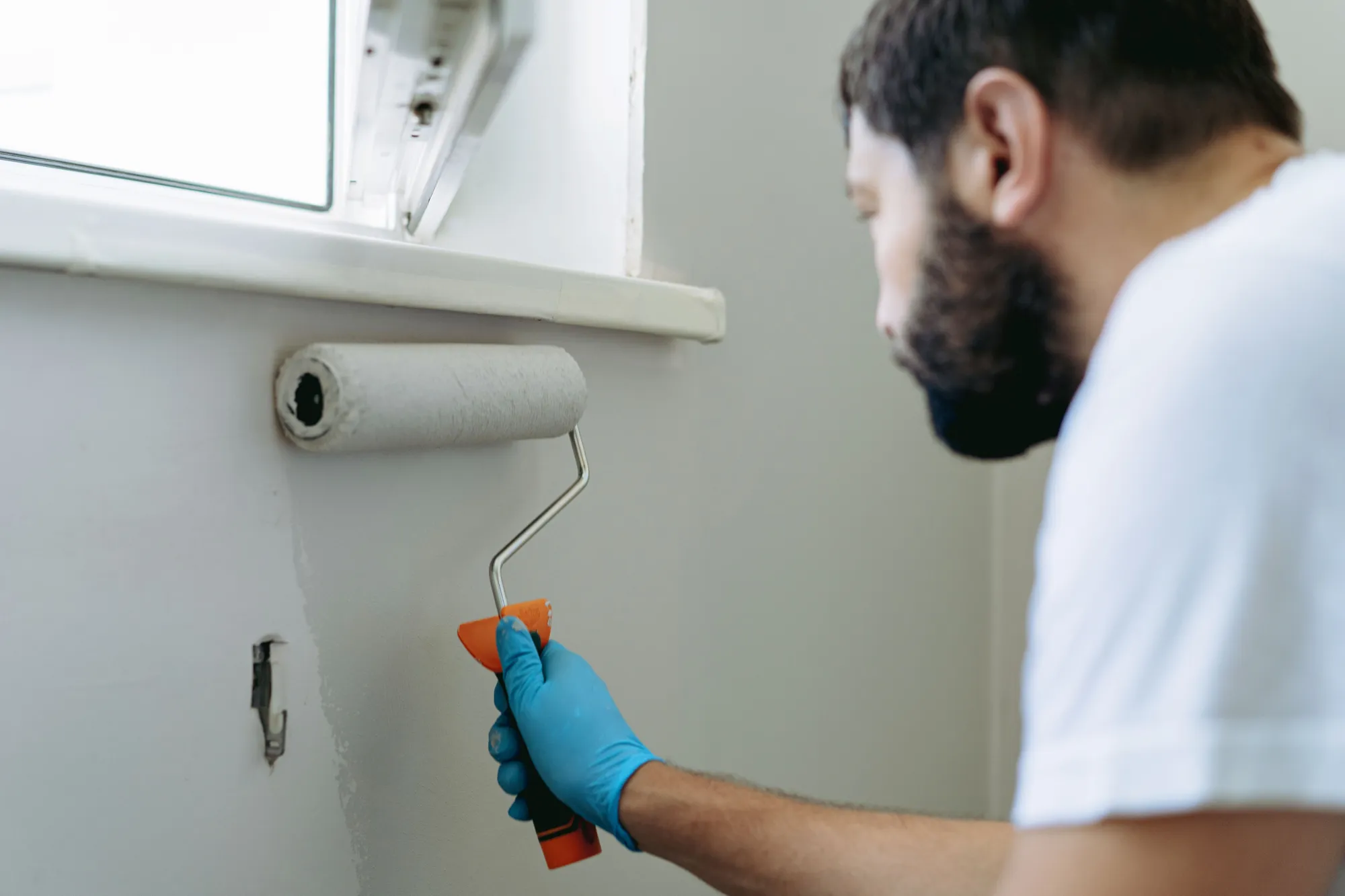 Maler streicht eine Wand mit dem Farbroller